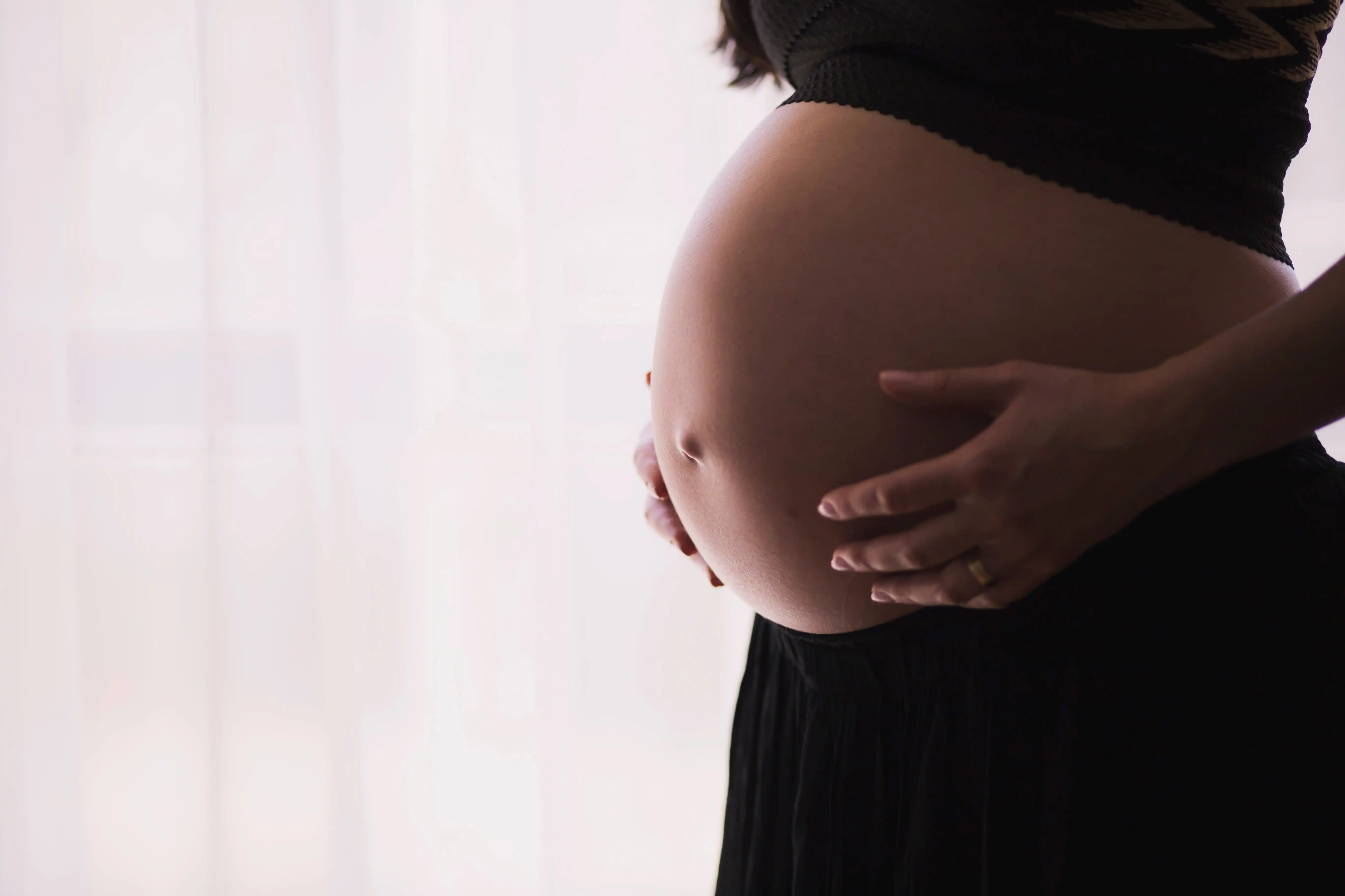 A pregnant woman gently holds her belly on 9th month.