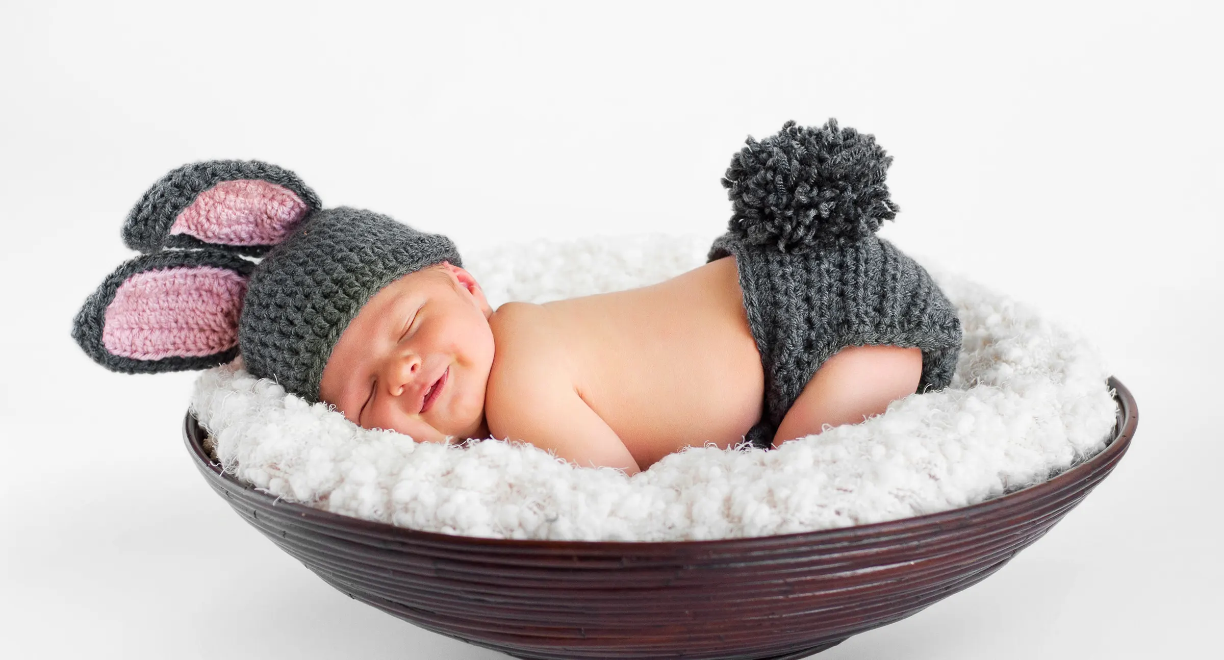 En glad baby, der lægger sig ned med kaninår hat.